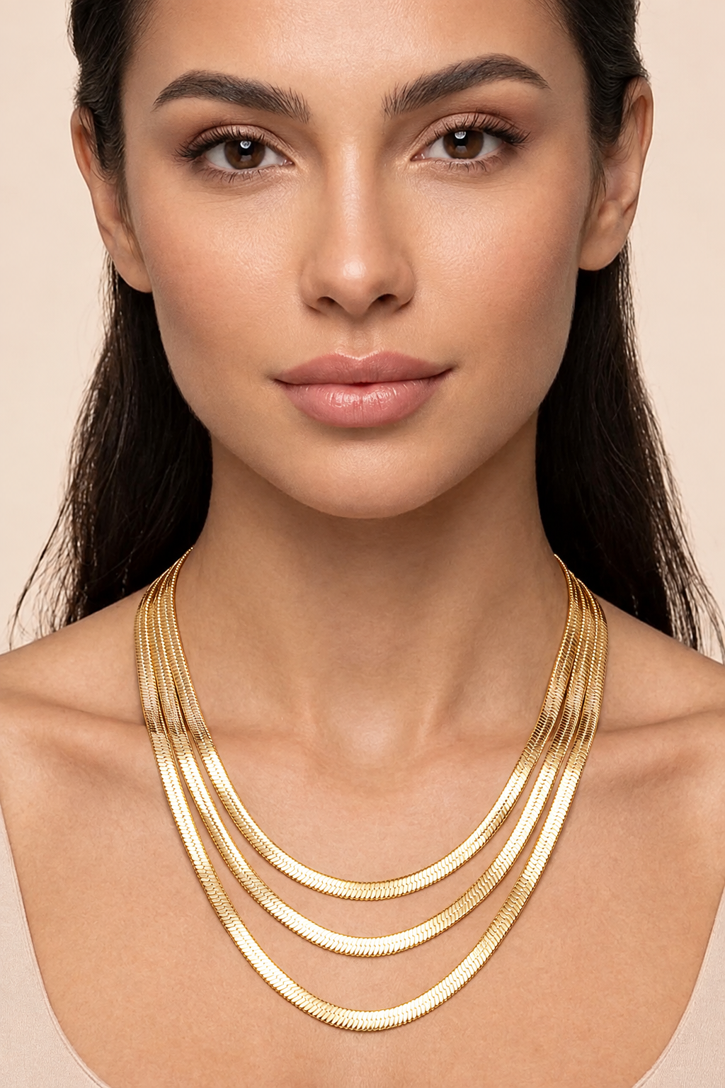 Model wearing gold dipped triple strand herringbone chain necklace